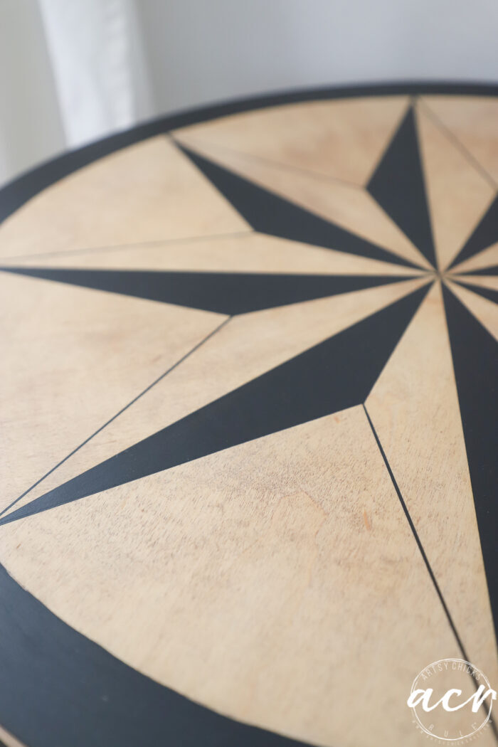 close up of table top with blonde wood and black compass rose