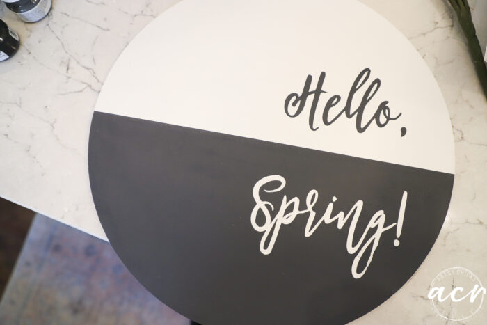 black and white spring round board with the words hello and spring on each half