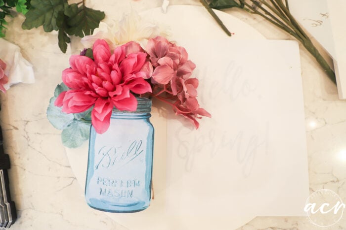 ball mason jar cutout with flowers arranged on white round board