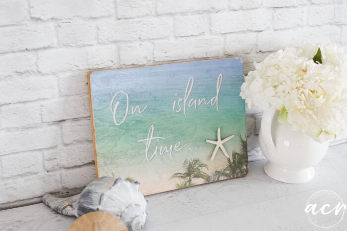 beachy sign with seashells and white vase and flowers