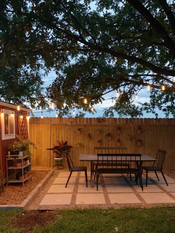 patio with table and chairs and string lights overhead