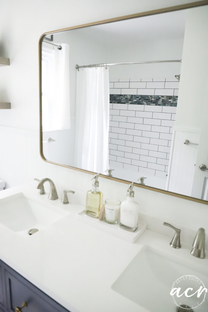 gold mirror with tiled shower in reflection