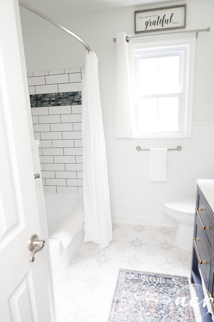 white bathroom with blue vanity and white shower tiled