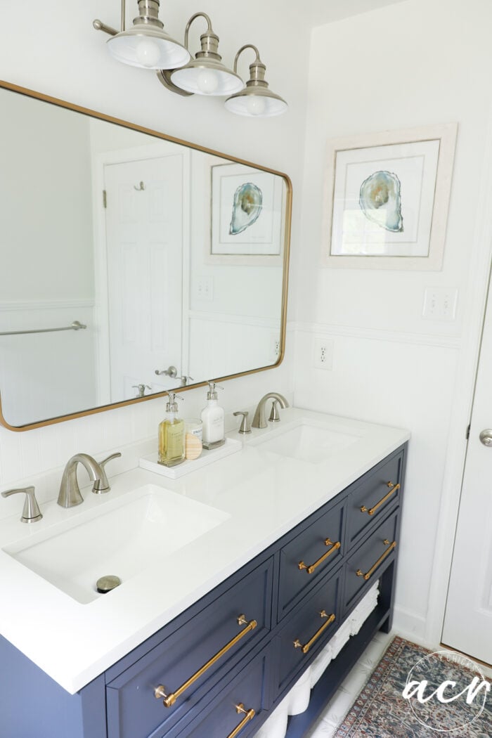 blue vanity, gold mirror, brushed nickel light