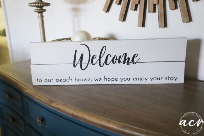 black and white welcome sign on blue dresser