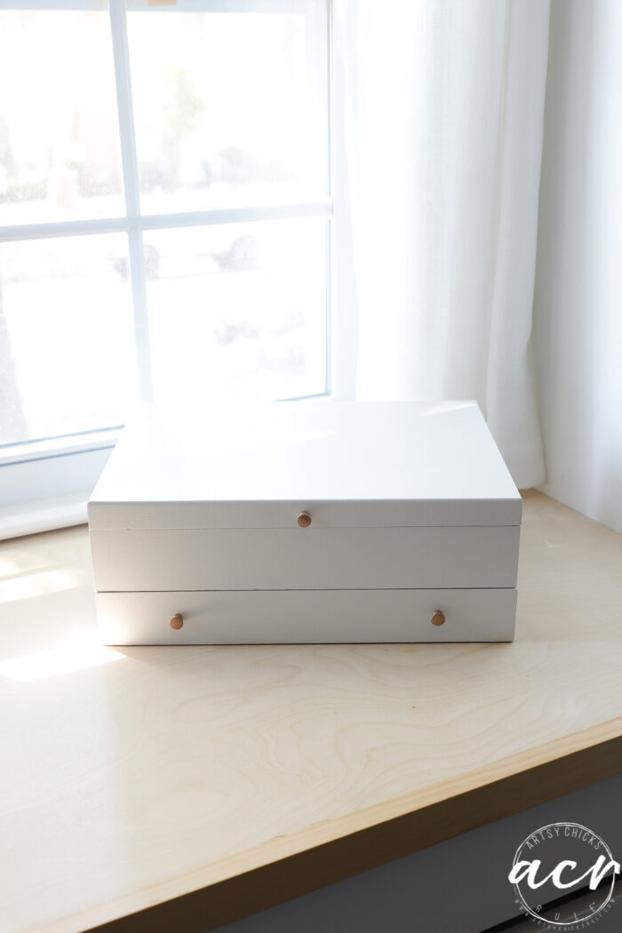 white box on wood dresser with window behind