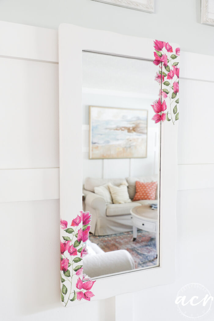 white framed wood mirror with dark pink flowers on the corners