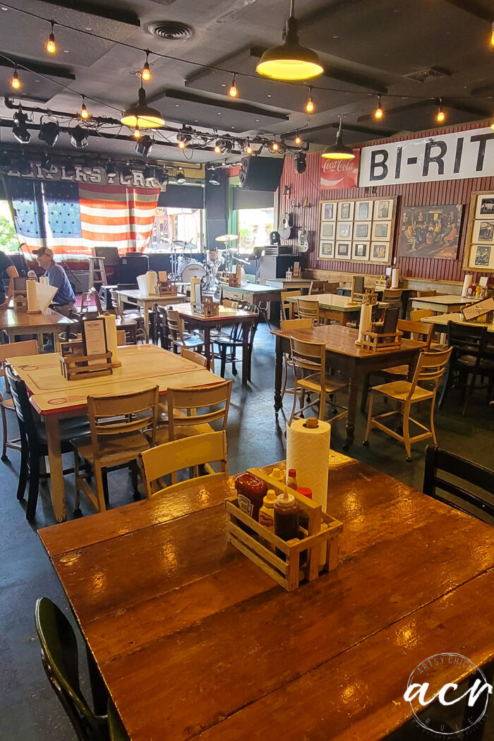 old different style tables and chairs with stage and american flag on window