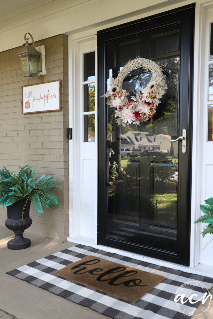 black front door with wreath and hello door mat