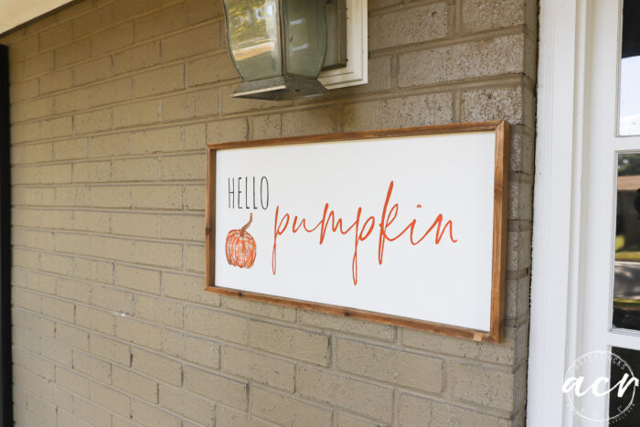 white wood framed hello pumpkin sign on brick wall