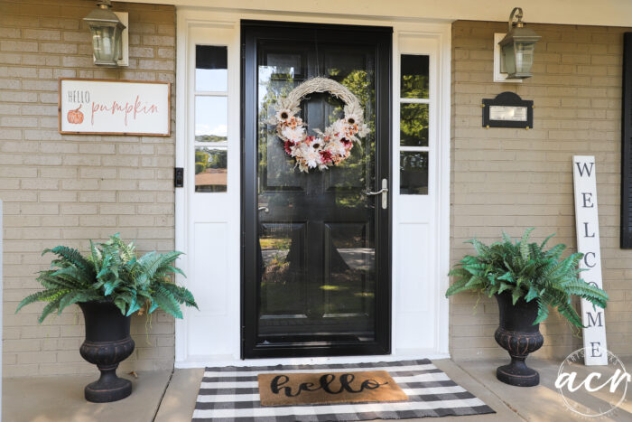 front view of front door and ferns, sign and door mat