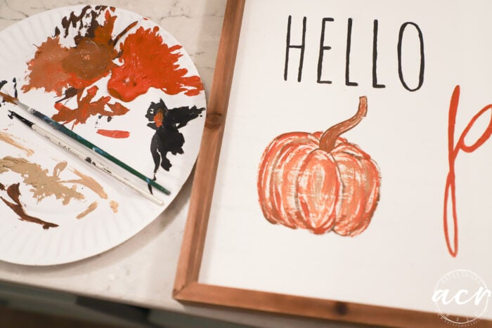 painted pumpkin on sign with paper plate and paints