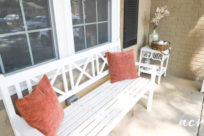 white bench with rust colored pillows