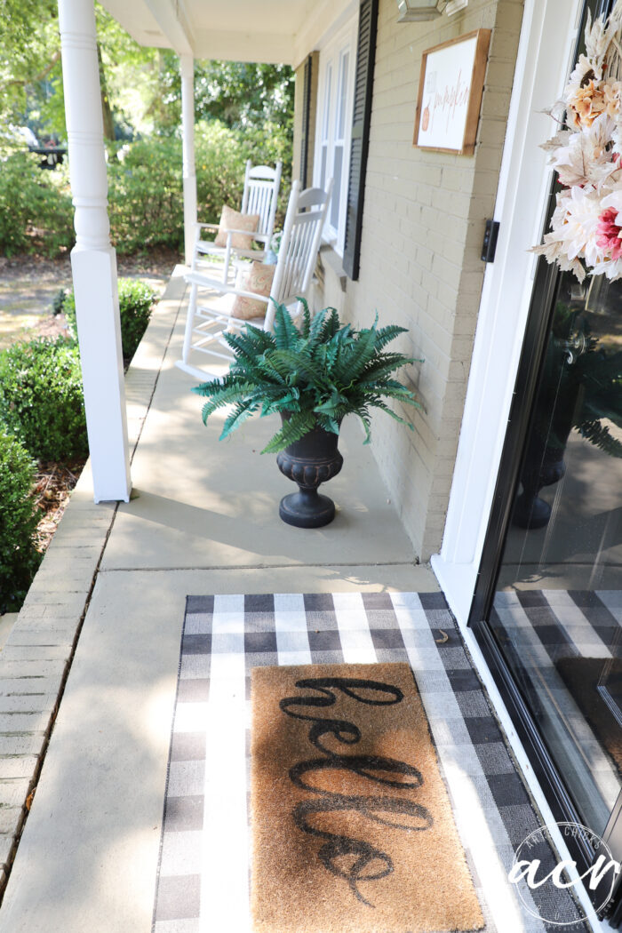 looking down porch with hello mat, green fern and white rockers
