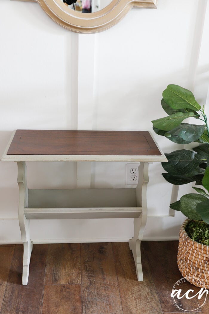 green table with stained top with plant beside