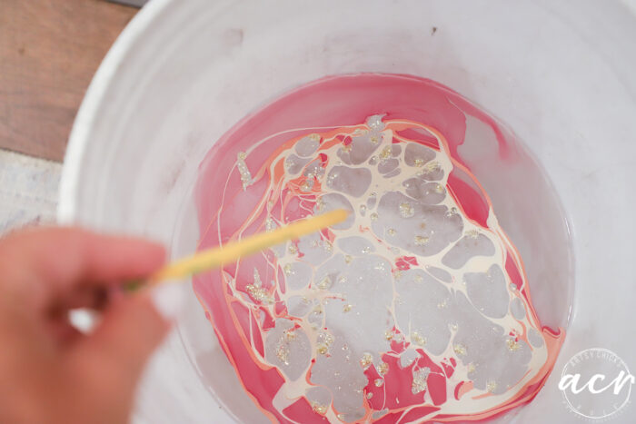 nail polish in bucket swirling with pencil
