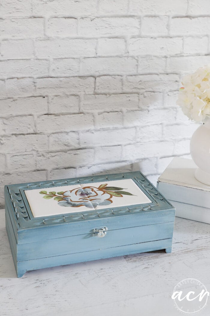 blue box with blue flower on top on white table