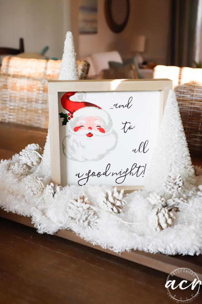 santa sign with gold frame in white snow and trees on table