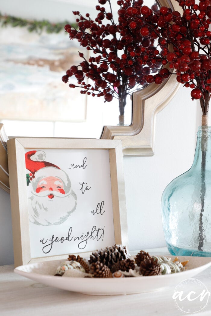 santa sign on white dresser with bowl of small pine cones in front