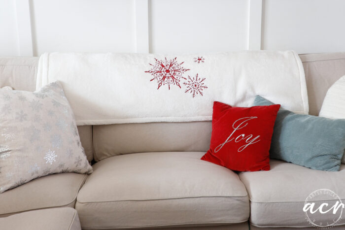 tan couch with snowflake throw and red pillow