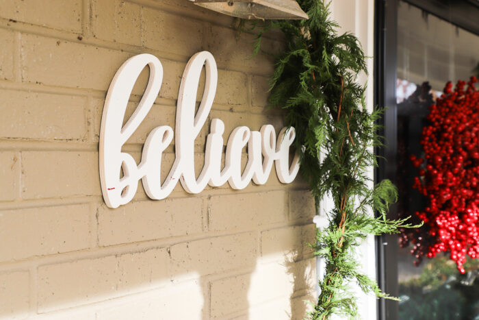 believe sign on brick wall of porch