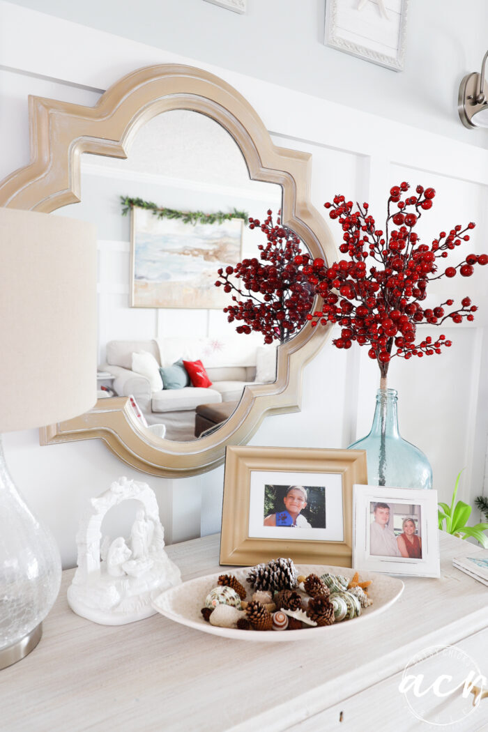 white dresser with red berries in aqua vase