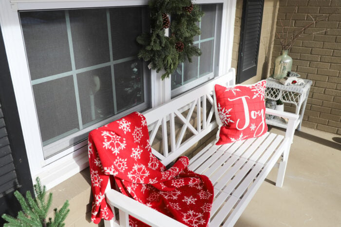 red blanket and pillow on white bench