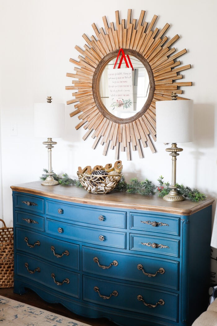medium blue dresser with wood starburst mirror above