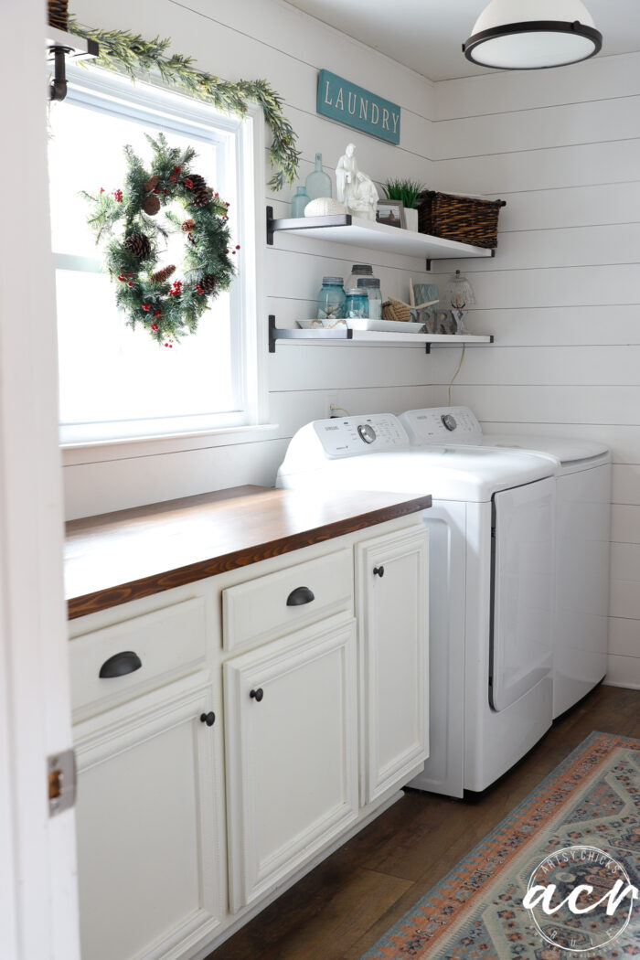 laundry room with long wood counter, washer and dryer and open shelves on wall