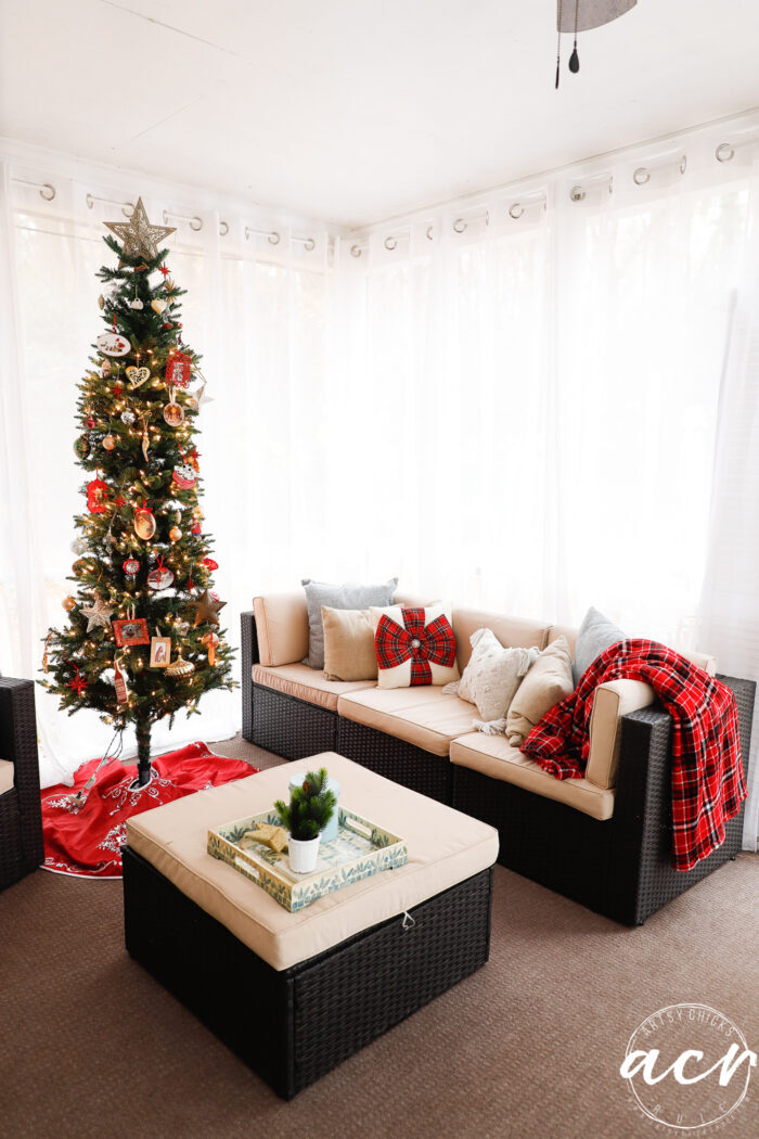 screened porch with red decor and skinny christmas tree