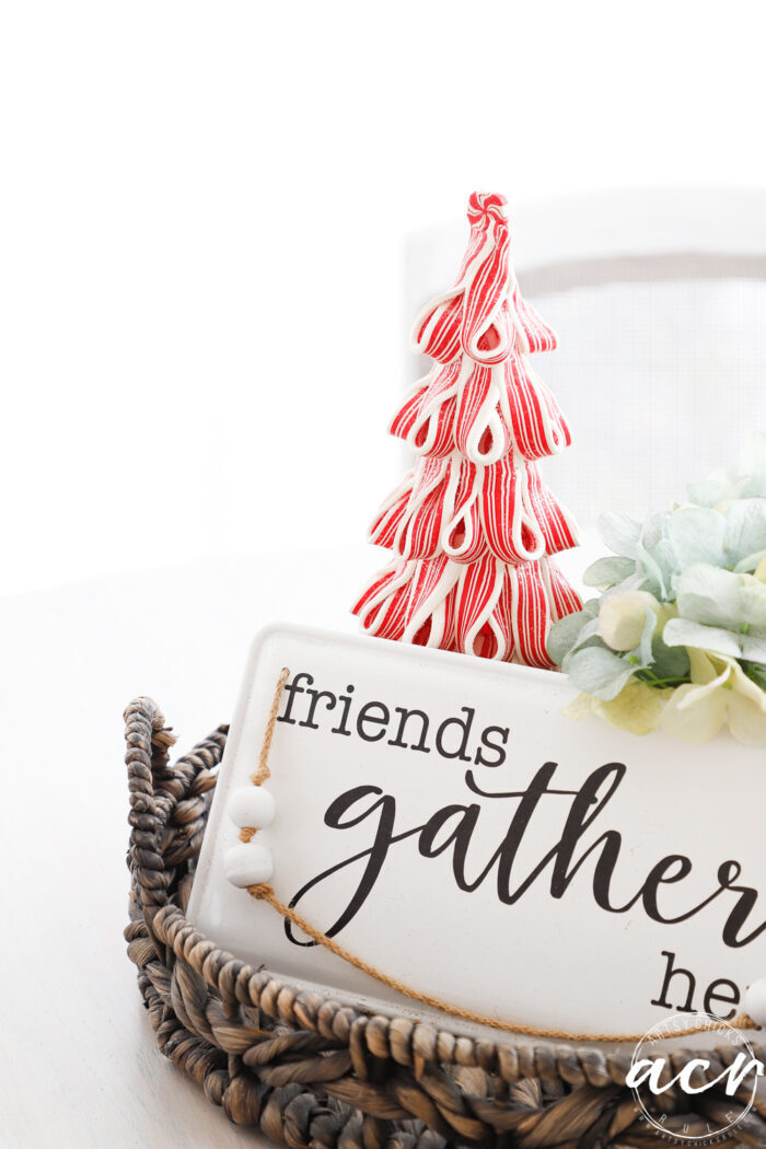 friends gather here sign on table with red and white christmas tree behind