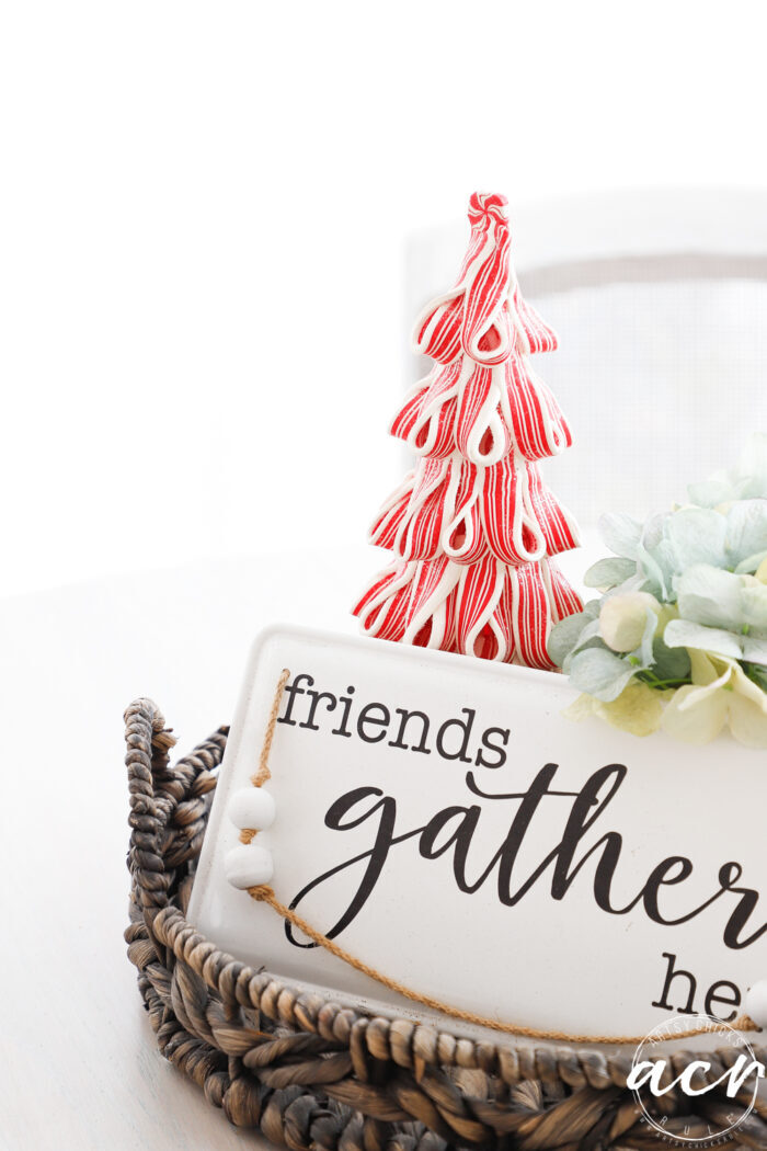 friends gather here sign on table with red and white christmas tree behind