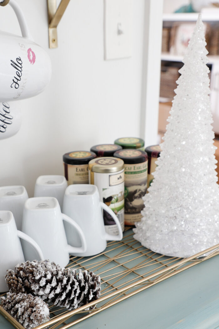 white sparkly christmas tree with pines cones, coffee mugs and tea canisters