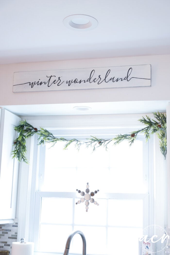 greenery over window with sign above and mirrored star in window