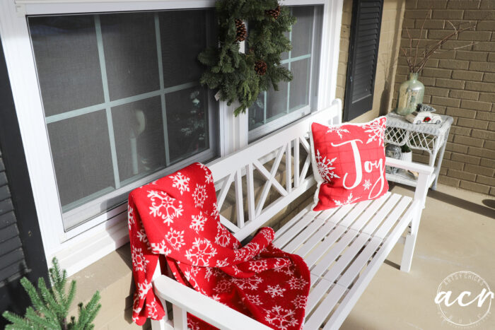 red blanket and pillow on white bench