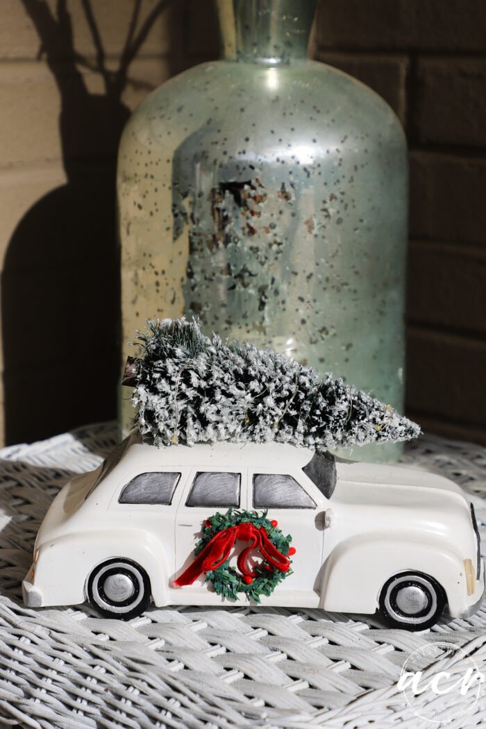 white ceramic antique car with wreath on door and christmas tree on top