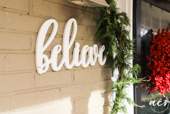 believe sign on brick wall of porch