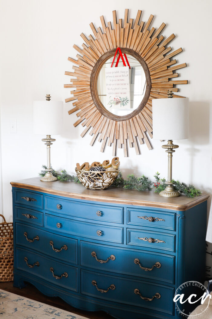 medium blue dresser with wood starburst mirror above