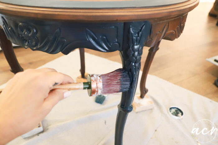 painting base of table blue with paint brush