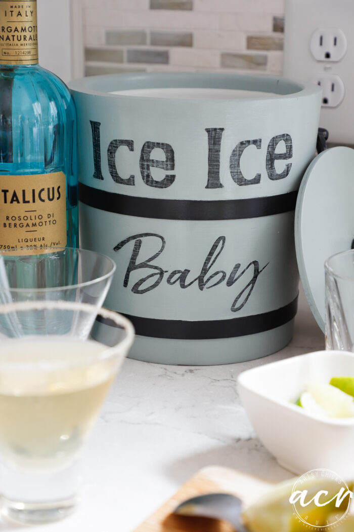 ice bucket on counter with cocktail and aqua liquor bottle