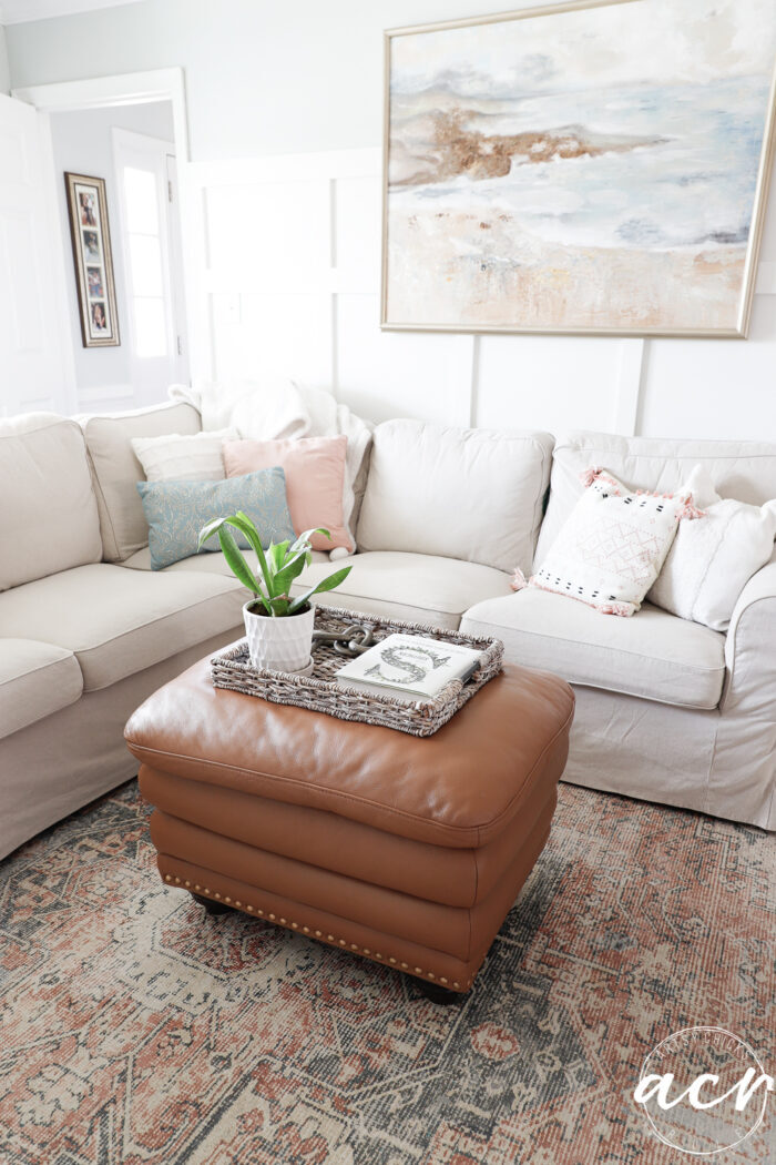 tan couch with leather ottoman and rug