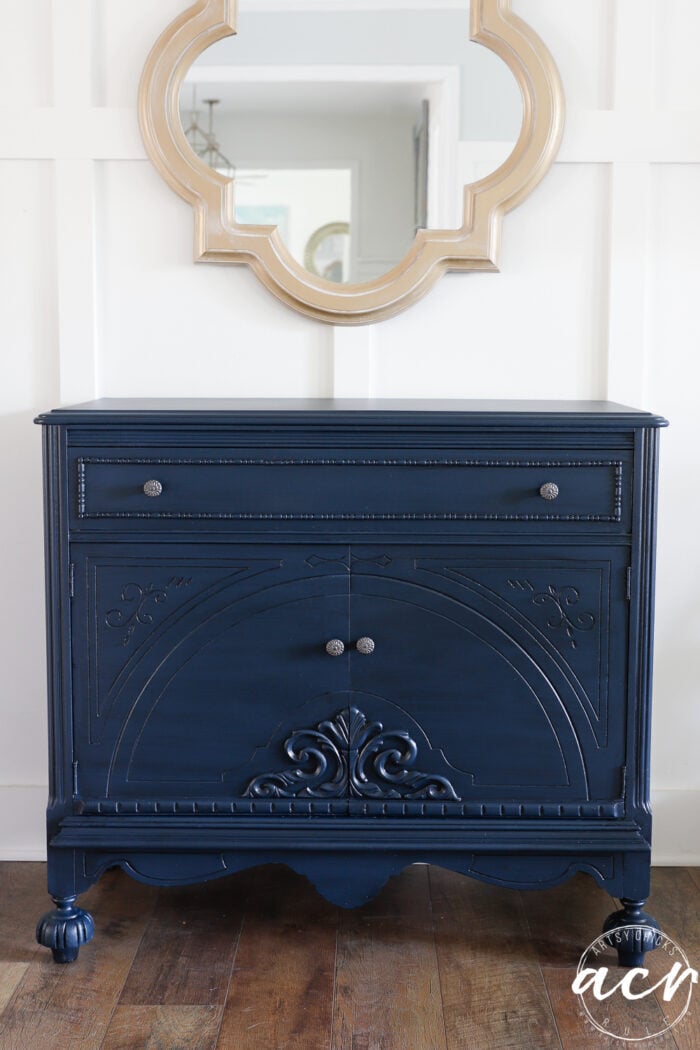 dark blue black glazed cabinet finished by white wall and gold mirror