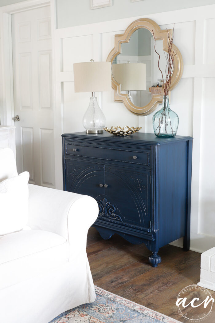 blue cabinet with decor on white wall and gold mirror