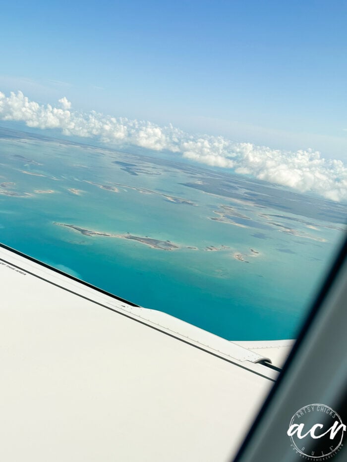 Looking out of the window of the airplane at the islands below and blue green water