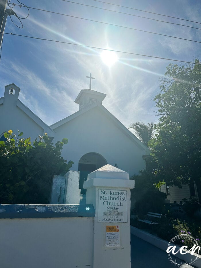 white church with steeple cross and sun with rays above it