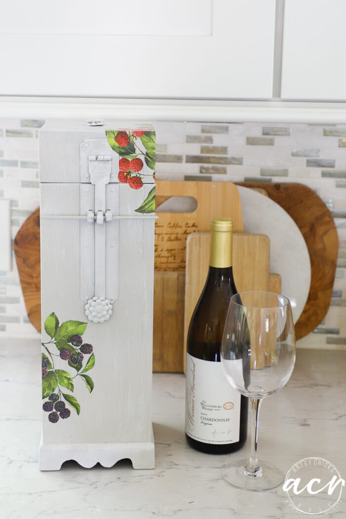 front view of finished wine box on counter with wine bottle and glass and cutting boards behind