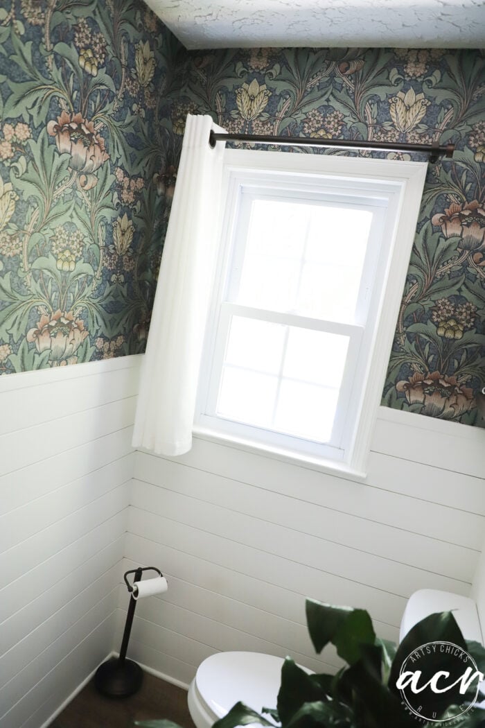window with white curtain and white shiplap with colorful wallpaper above
