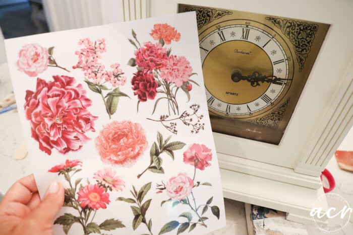 page of pink and rose colored floral transfers in front of clock