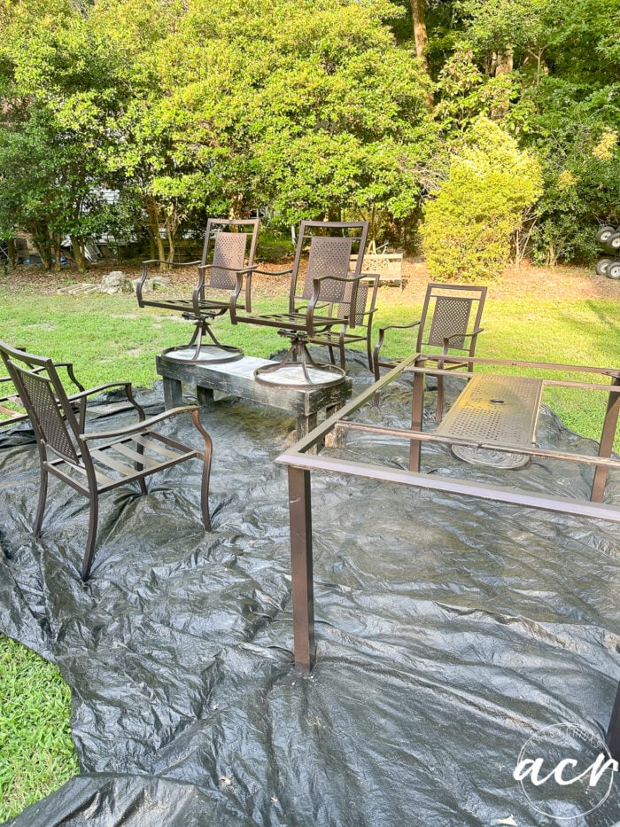 black tarp on grass with bronze/brown colored chair table set