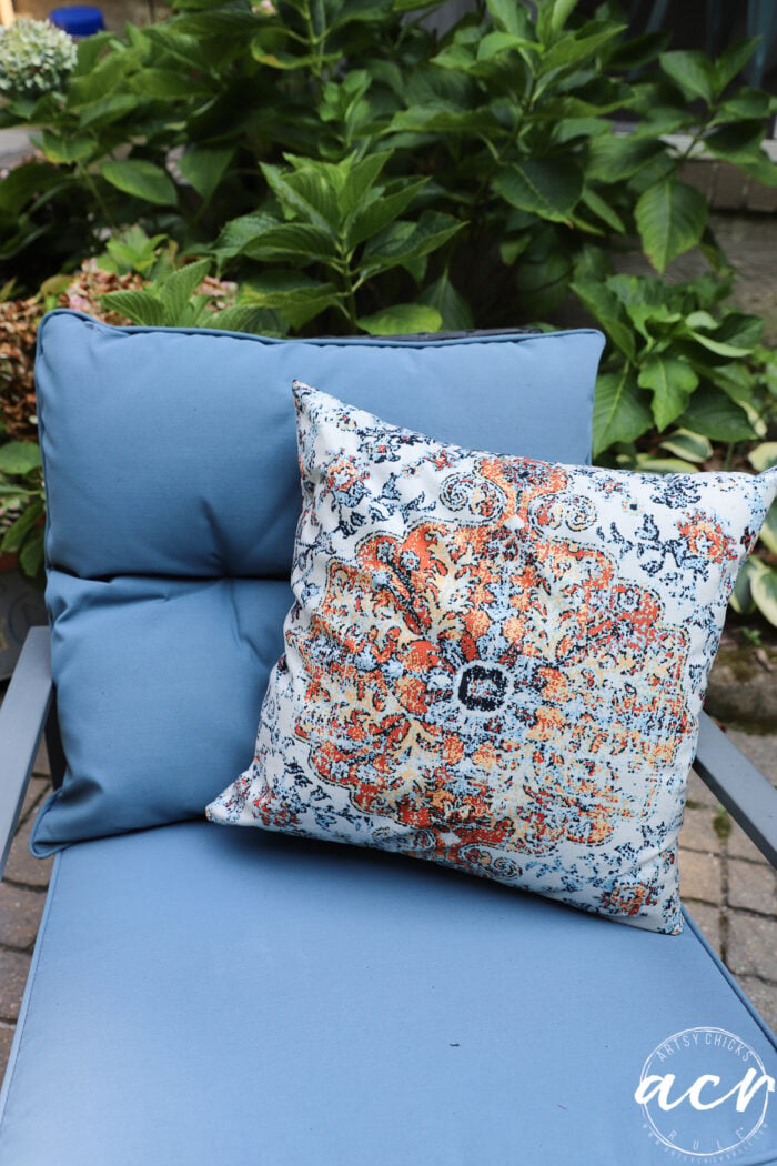 blue cushioned chair with orange and blue pillow